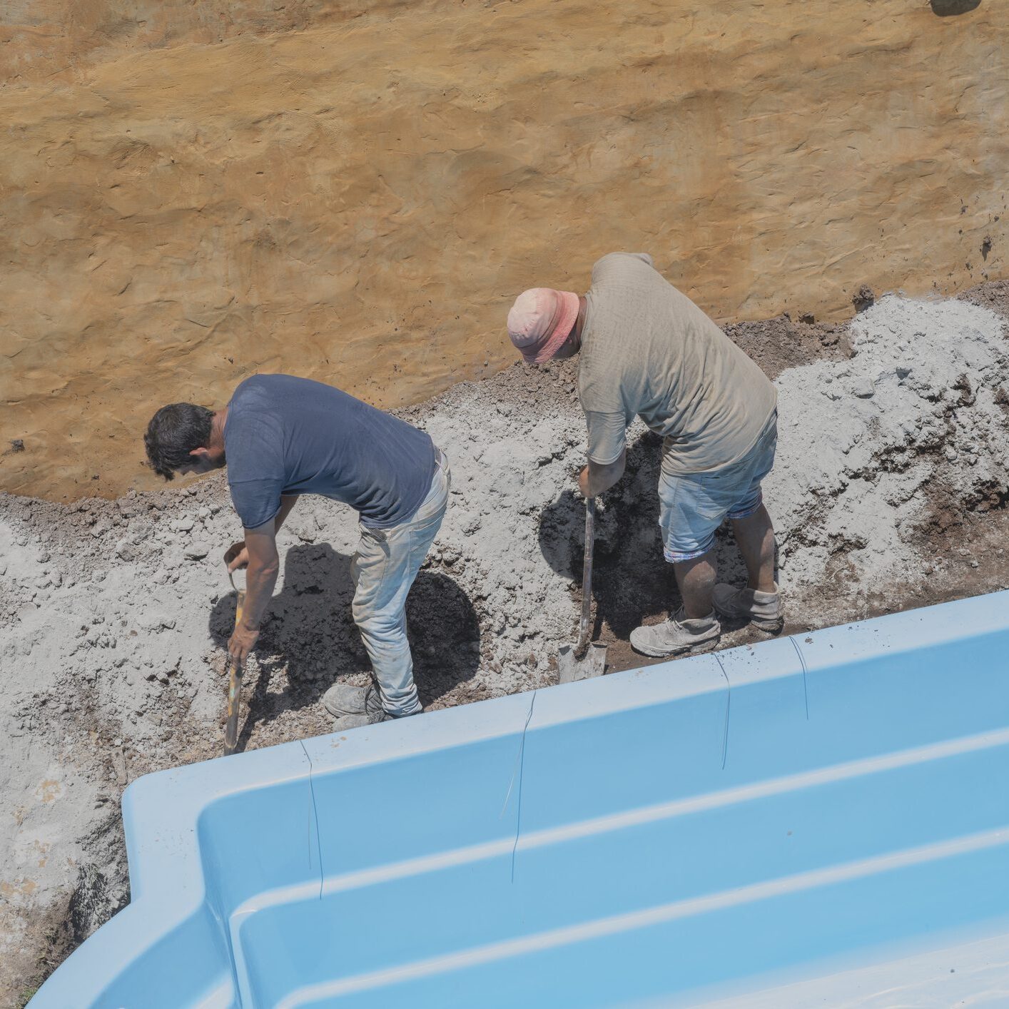 Workers digging ground beside a swimming pool.